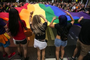 Amanda DeBlois and Carla Moreno, right, dance while helping to carry a huge rainbow flag for the 41st Annual Seattle Pride Parade in downtown Seattle on Sunday, June 28, 2015. (Bettina Hansen/Seattle Times/TNS)