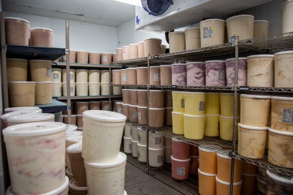 Large containers of Aggie Ice Cream are stored in a large freezer.