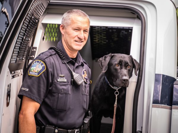 USU officer Murray stands with new police dog Zoomer by his patrol vehicle.