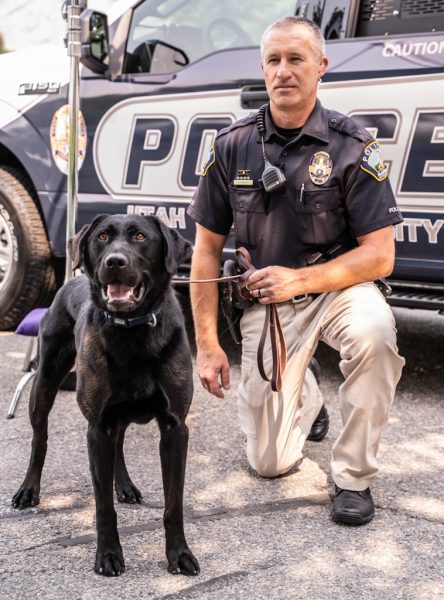 USU officer Murray stands with new police dog Zoomer by his patrol vehicle.