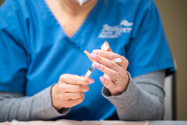 A Bear River Health Department nurse fills a vaccine at USU's on-campus clinic.